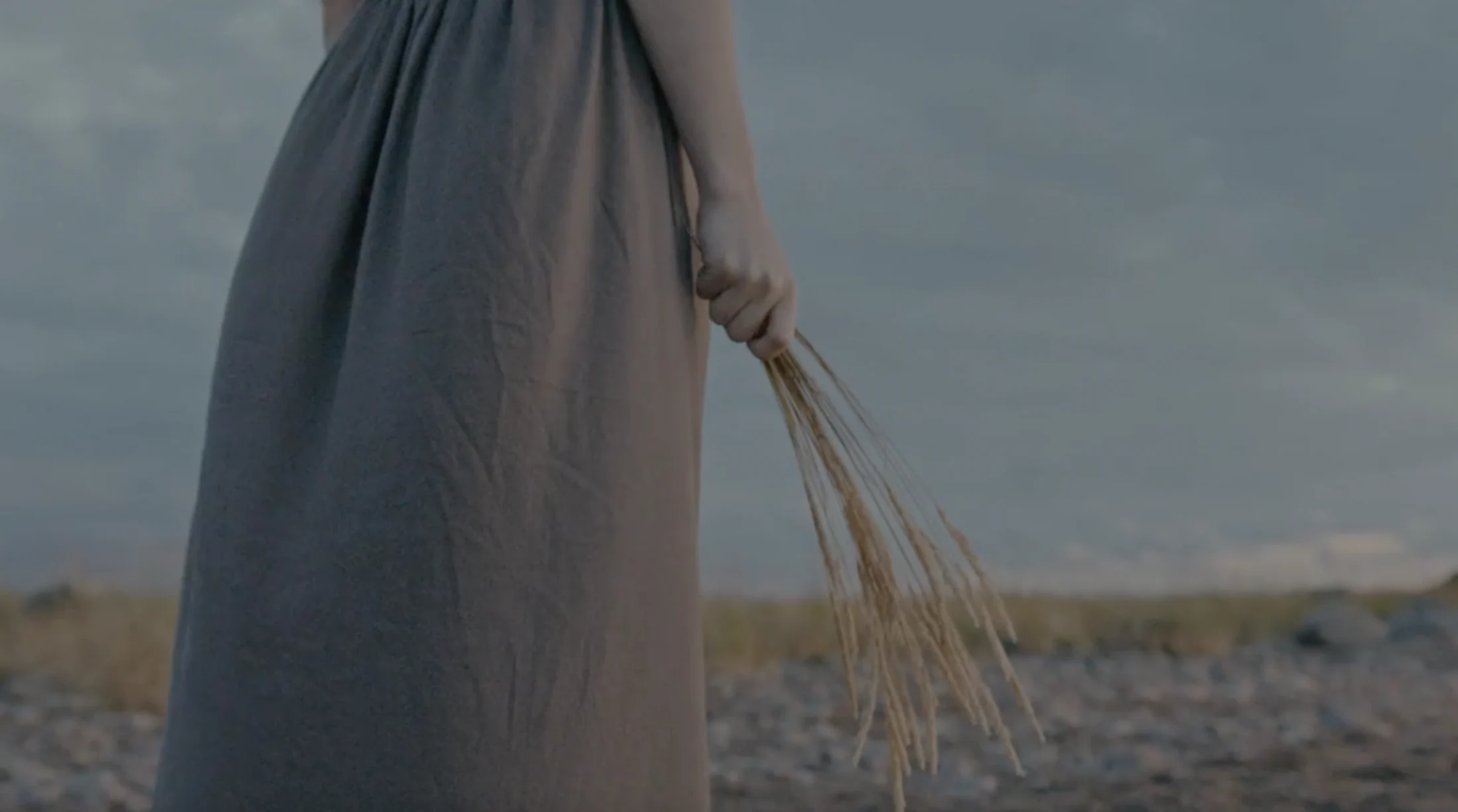 A woman holding wild grasses beside the water, from Dr. Michele Burklund’s original homepage film