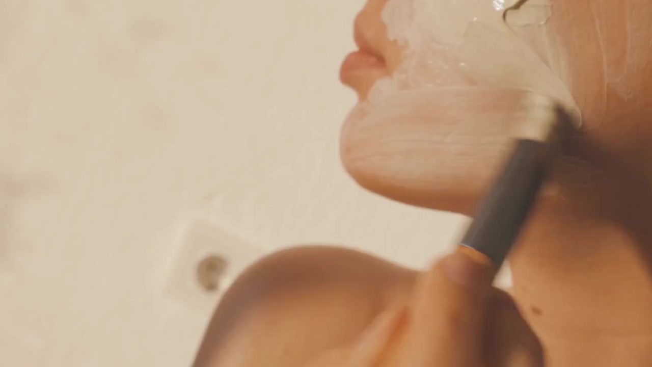 A facial mask being gently applied with a brush