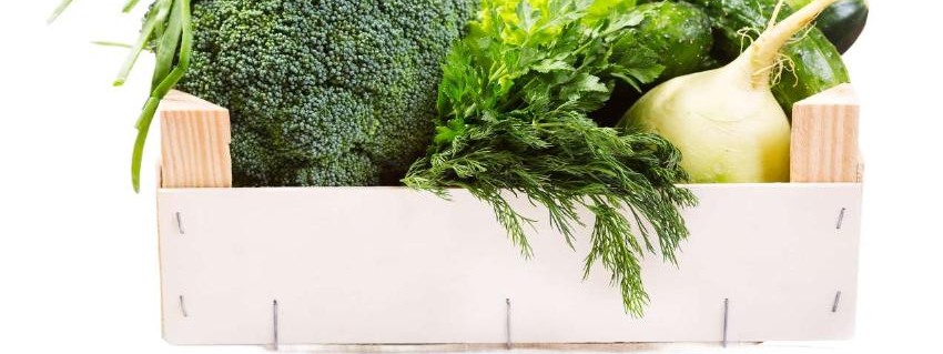 A wooden crate filled with fresh vegetables and herbs
