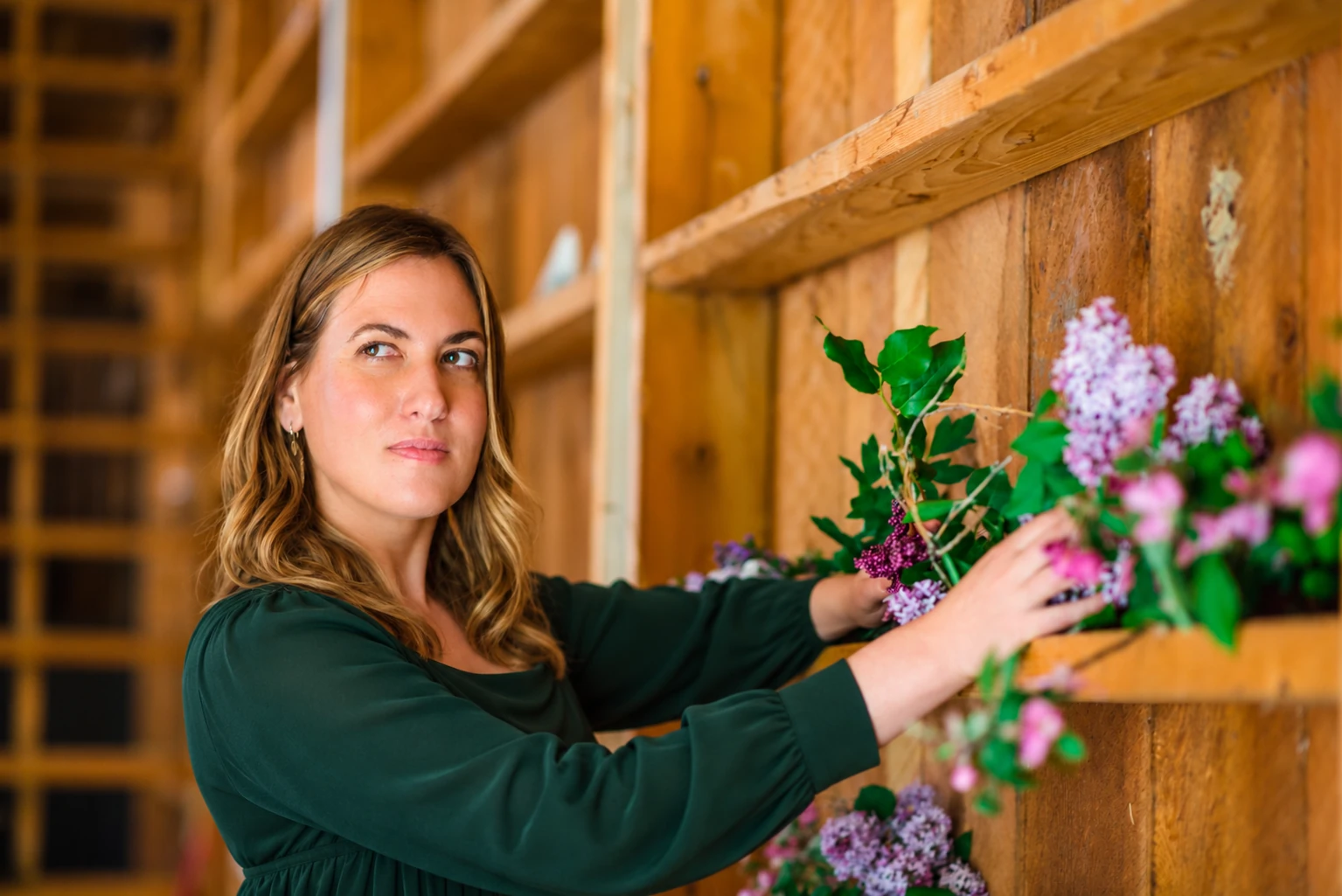 Dr. Michele Burklund in a forest-green dress arranging botanicals