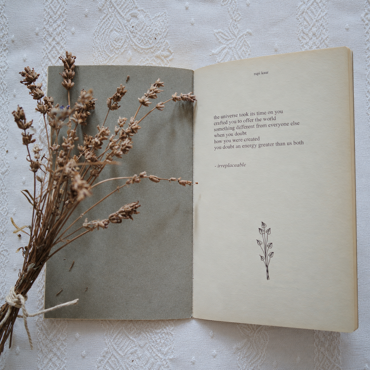 An open poetry book with dried lavender across the left page on a lace-covered table
